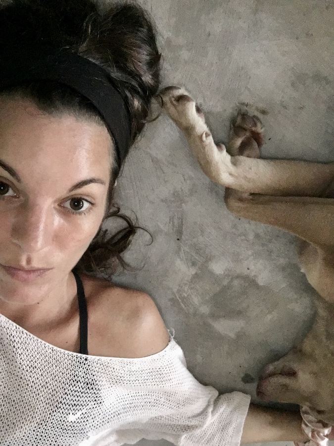 Laura Link liegt neben einem Hund auf einem Betonboden
