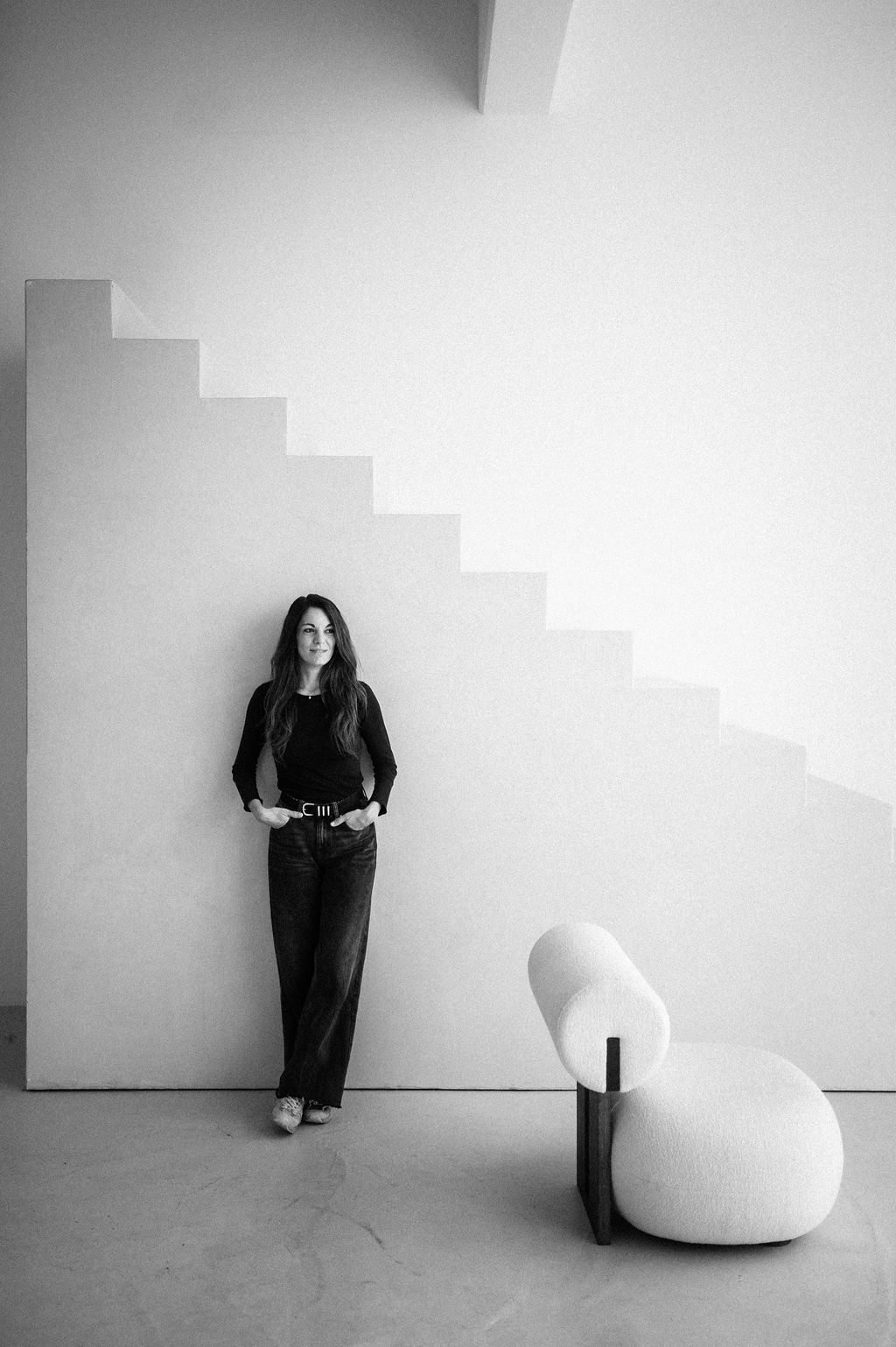 Laura Link steht an einer weißen Wand unter einer Treppe